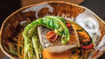 Ein Teller mit Fisch, grünen Gemüsesorten und roten Chilischoten.