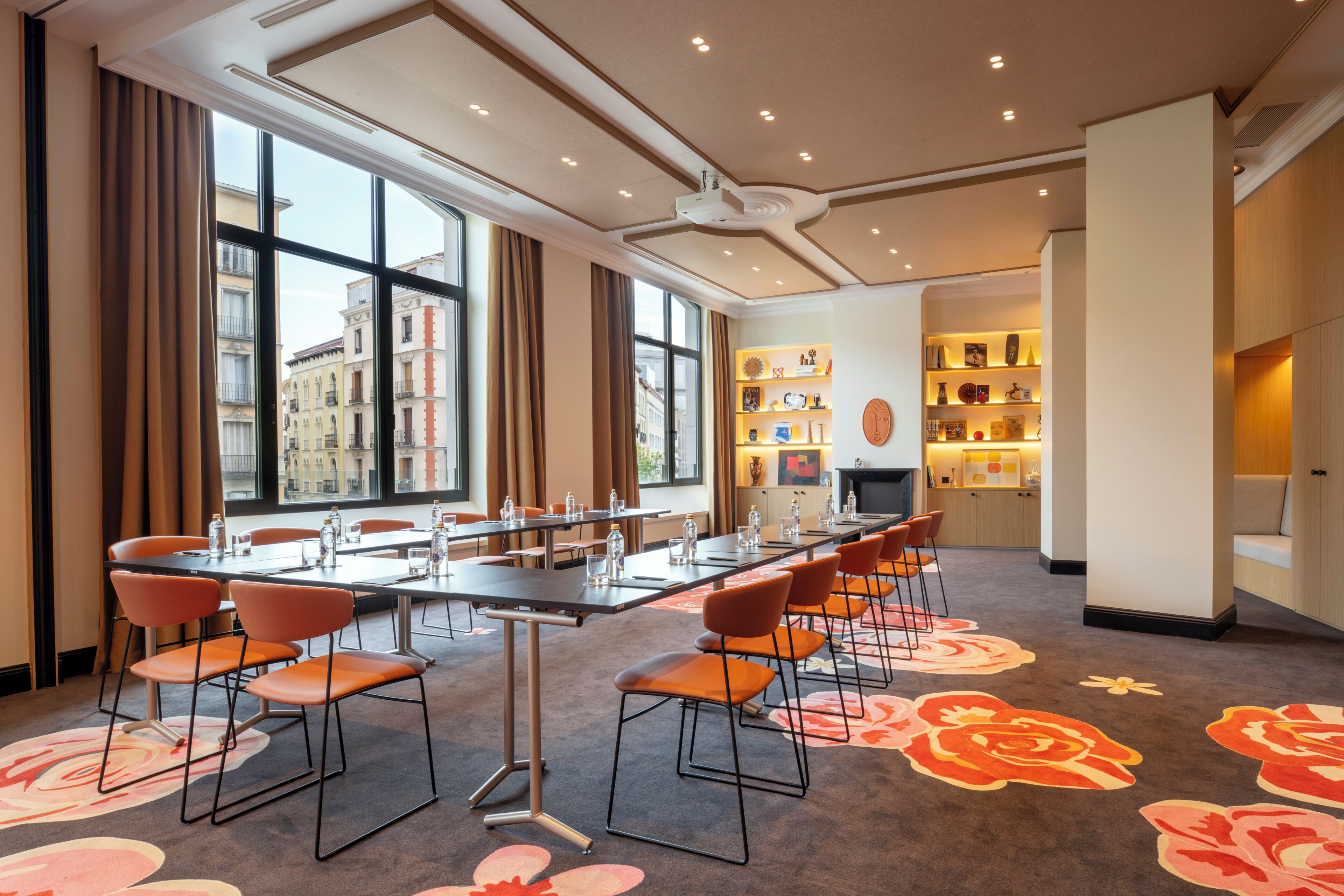 A conference room with a long table, chairs, and a carpet with floral patterns.