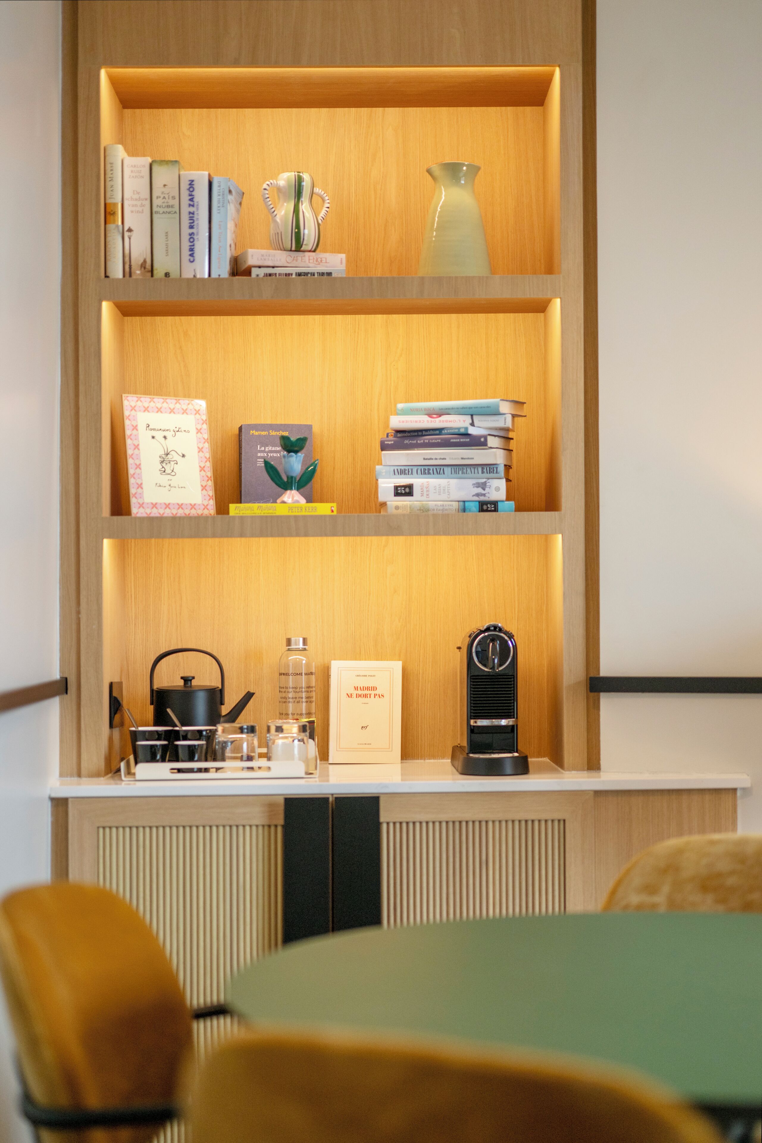 Une bibliothèque avec des livres, un vase et une horloge.