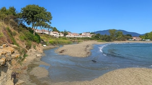 A beach with a river flowing into the sea, surrounded by buildings with red roofs. - Apartment T3 Marine de Bravone feet in the water (Linguizzetta)
