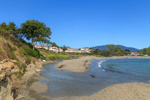 A beach with a river flowing into the sea, surrounded by buildings with red roofs. - Apartment T3 Marine de Bravone feet in the water (Linguizzetta)