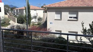 A residential building with a tiled roof, a balcony, and a sign indicating room B1. - Apartment T3 Marine de Bravone feet in the water (Linguizzetta)