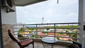 Een balkon met een stoel, een tafeltje en uitzicht op een stadsgezicht, inclusief een toren.
