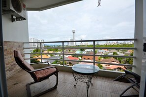 Ein Balkon mit Stuhl, Tisch und Blick auf eine Stadtlandschaft, einschließlich eines Turms.