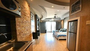 Een moderne hotelkamer met een kitchenette, een bed en een koelkast.