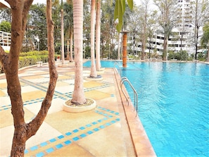 A swimming pool with a tiled deck and palm trees. - Sea-view Studio With Large Balcony - Bright and Spacious (Pattaya)