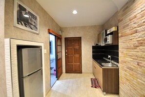 Eine kleine Küche mit Kühlschrank, Mikrowelle und Spüle.