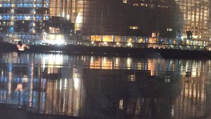 Ein großes, modernes Gebäude mit einer geschwungenen Fassade, die sich im Wasser vorneweg spiegelt.