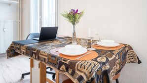 Ein Esstisch, gedeckt mit Tellern, Besteck und einer Vase mit Blumen.
