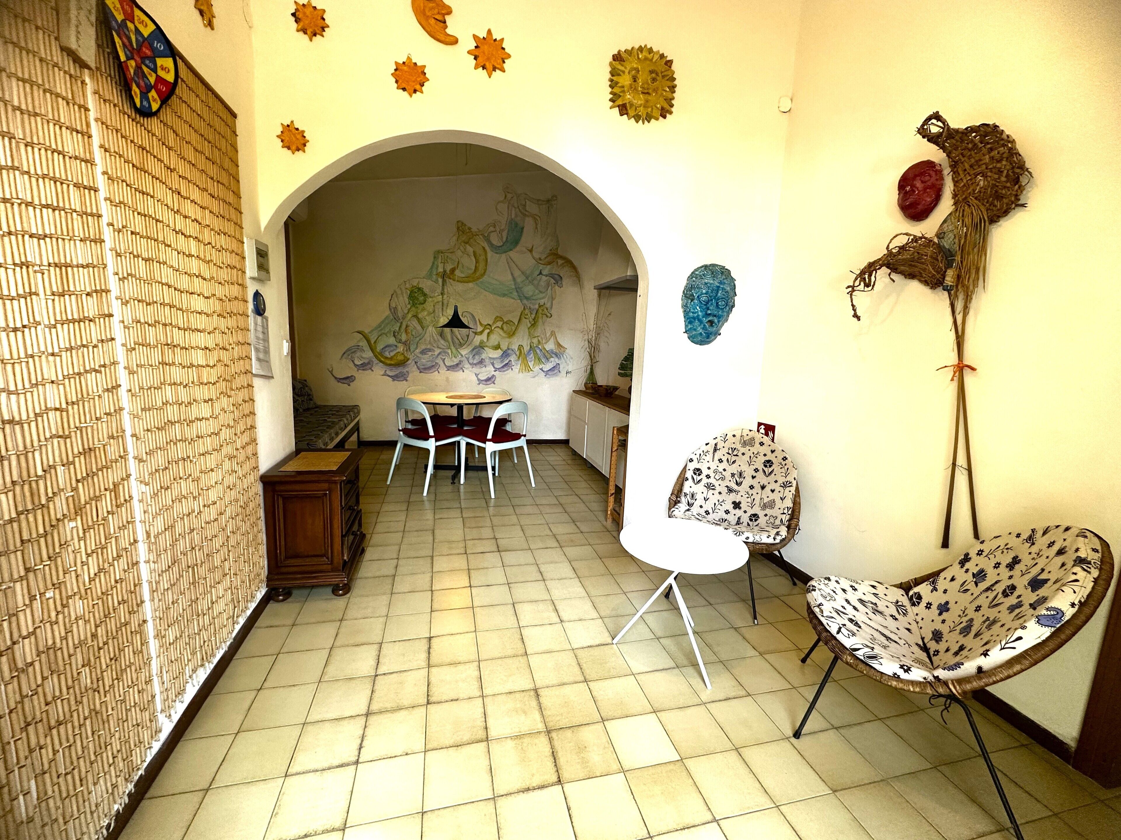 A dining area with a round table and chairs, a decorative wall mural, and a unique ceiling design.