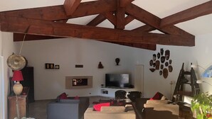 Ein Wohnzimmer mit hoher Decke, einem Fernseher und einem Kamin.