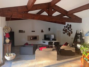 Ein Wohnzimmer mit hoher Decke, einem Fernseher und einem Kamin.
