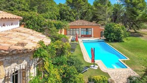 Eine Villa mit Swimmingpool, Steinmauern und Garten.