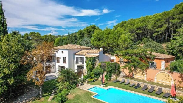 Eine Villa mit Swimmingpool, umgeben von üppiger Vegetation und Hügeln.