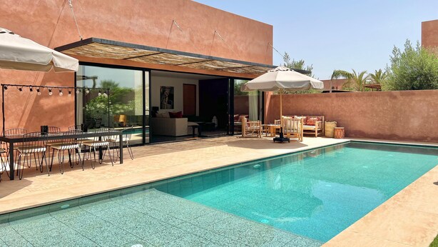 Een modern zwembadterras met een glazen patio, buitenmeubels en een helderblauw zwembad.