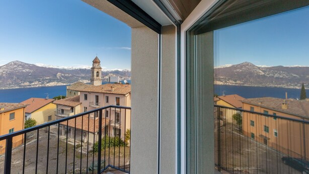 A balcony with a view of a town, a church tower, and mountains in the distance. - Giulio's Apartment First Floor (San Zeno di Montagna)