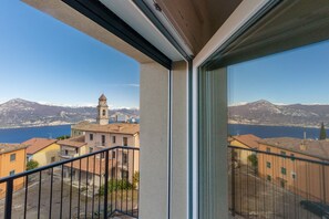 Uma varanda com vista para uma cidade, uma torre de igreja e montanhas ao longe.