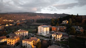 A residential area with multiple two-story buildings, a main road, and surrounding hills. - Giulio's Apartment First Floor (San Zeno di Montagna)