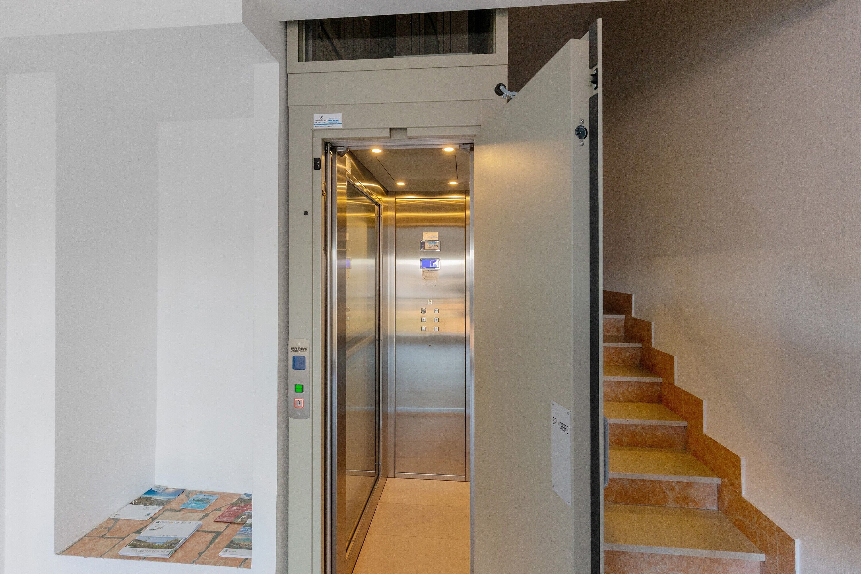 An elevator with a control panel, a staircase with a sign, and a wall with a bulletin board.