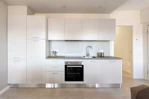 Una cucina moderna con elettrodomestici in acciaio inox, mobili bianchi e forno integrato.