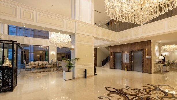 Un'ampia hall con pavimento lucido, eleganti lampadari e una maestosa scalinata.