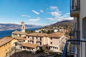 Una località costiera con un'imponente torre campanaria, edifici a terrazze e vista sul mare e sulle montagne.