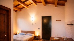 Une chambre confortable avec un lit en bois, des lampes de chevet, une porte sombre et un coin repas avec une table mise pour deux personnes.