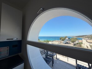 Ein Zimmer mit einem großen Rundfenster, das Meerblick und eine ferne Küstenlinie bietet.