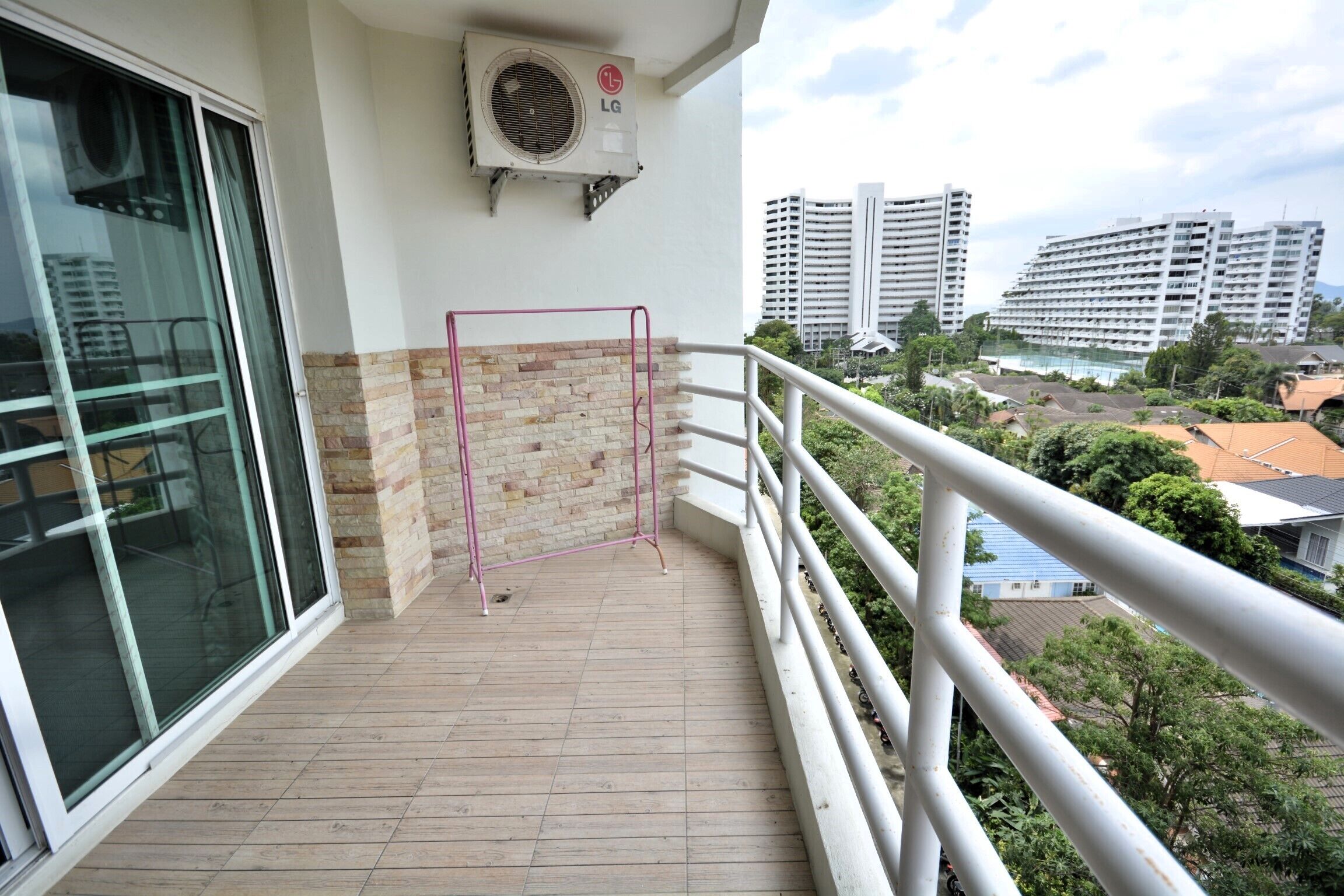 A balcony with a metal railing, a brick wall, and an air conditioning unit.