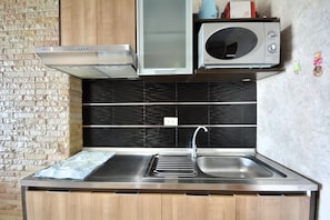 A kitchen with a stainless steel sink, a microwave, and a built-in oven. - Sea-view Studio With Large Balcony - View Talay 5D (Pattaya)
