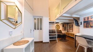 A modern interior with a white console table, a ladder, a dining area with a table and chairs, and a mounted TV. - M (JJU15503) Duplex with terrace in Goya (Madrid)