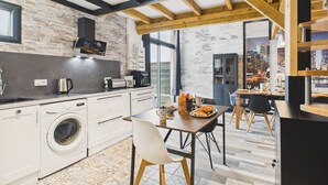Eine moderne Küche mit Steinwand, Holzbalken und einem großen Fenster mit Blick auf eine Stadtlandschaft.