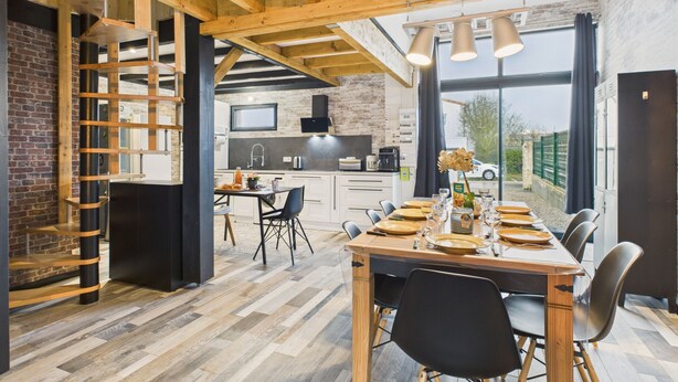 Eine moderne Küche mit freiliegenden Holzbalken, einer Backsteinwand und einem großen Fenster.
