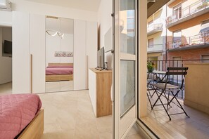Un dormitorio moderno con cama, armario y balcón con mesa y sillas.