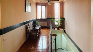 A hallway with a dining area, a staircase, and a view of a balcony with plants. - Aero Hotel (Parakar)
