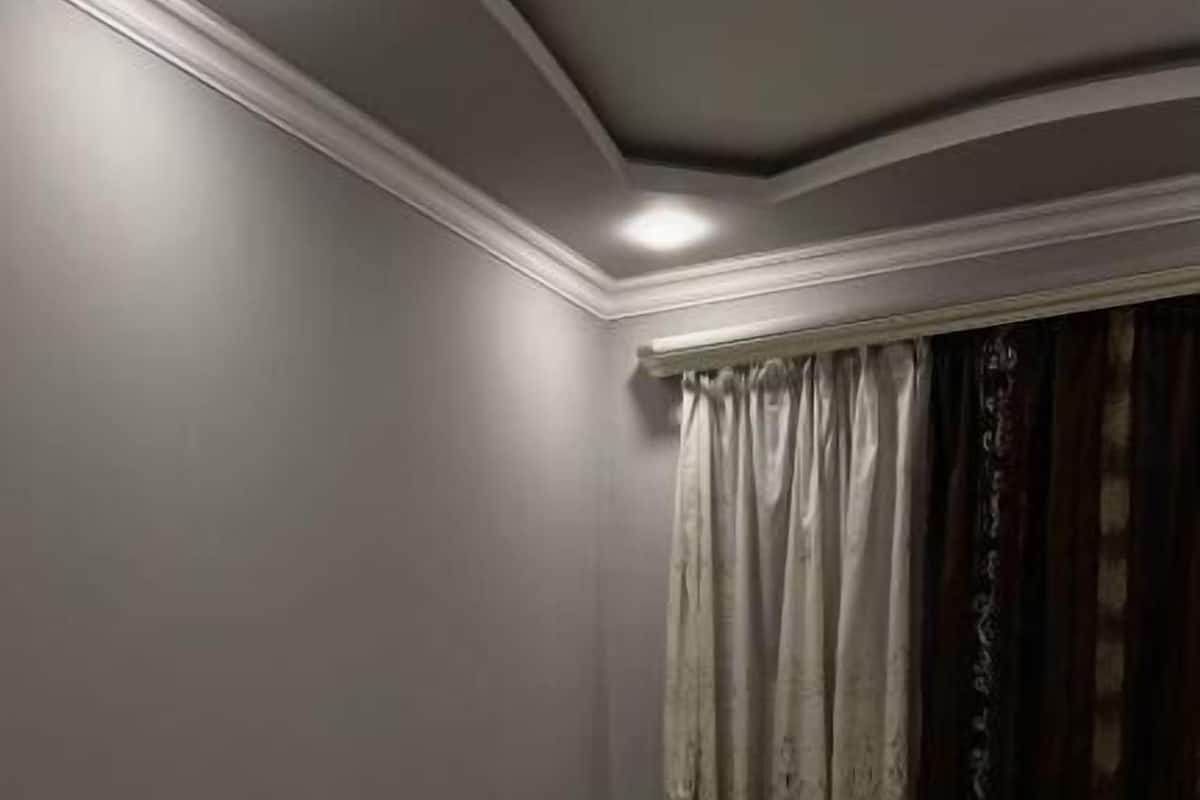 Ein Schlafzimmer mit einem Bett, grünen Nachttischen und einem Fenster mit Vorhängen.