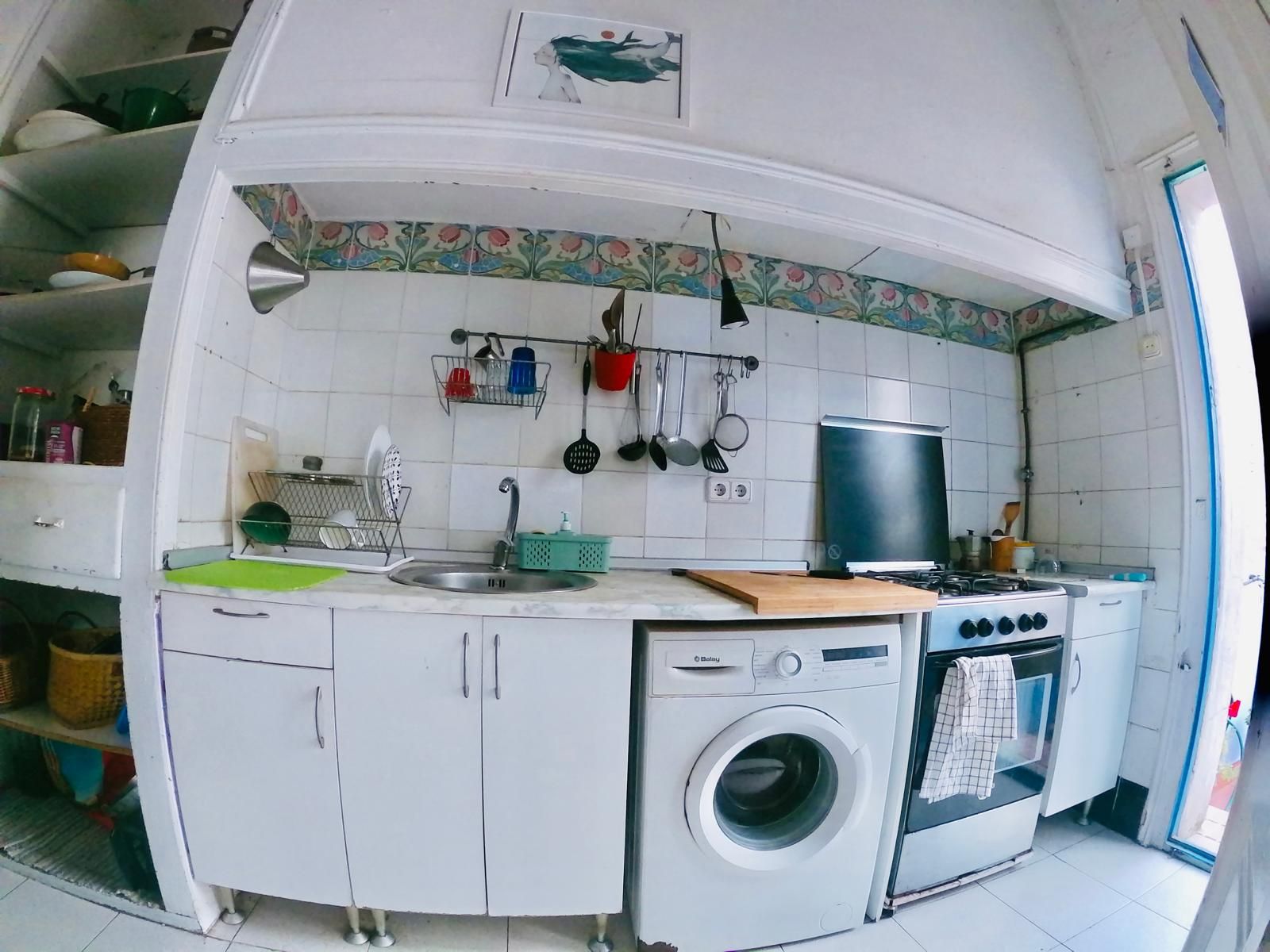 Uma cozinha compacta com máquina de lavar, fogão e pia.