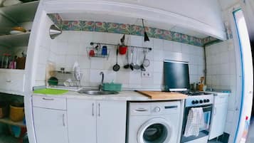 Uma cozinha compacta com máquina de lavar, fogão e pia.