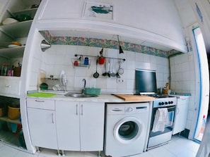Uma cozinha compacta com máquina de lavar, fogão e pia.