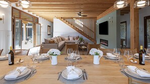 A spacious living area with a wooden staircase, a sofa set, and a dining table set for six with wine glasses and plates. - Rural house ORUE BASERRIA in URDAIBAI-with jacuzzi and sauna (Ajuria)