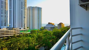 Un edificio residencial alto con varios balcones, rodeado de abundante vegetación y una vista despejada del océano.