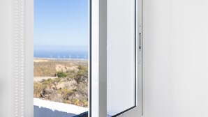 A window with a view of a coastal landscape, including vegetation and distant wind turbines. - Oasis Tenerife studio D (Granadilla de Abona)