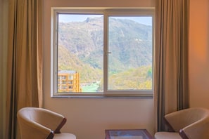 Ein Zimmer mit einem großen Fenster, zwei Stühlen und einem kleinen Tisch.