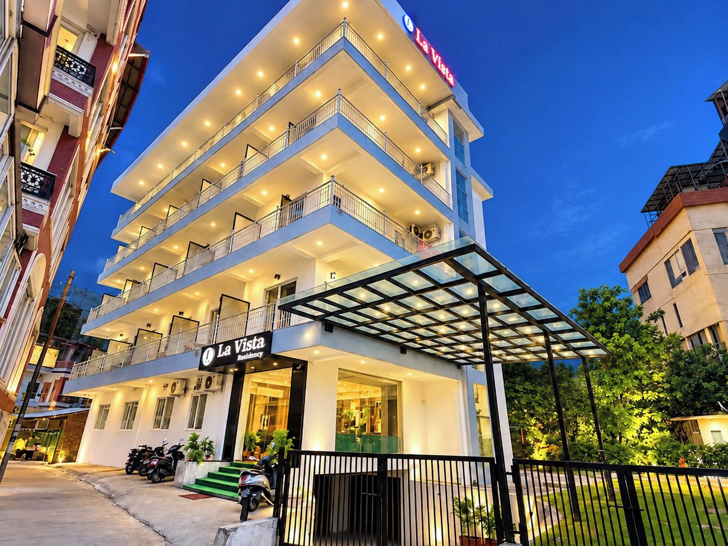 Un hotel de varios pisos con entrada de cristal y balcones.