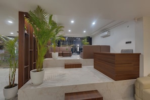 Un vestíbulo moderno con mostrador de recepción, zona de estar y plantas en macetas.