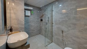 A modern bathroom with two sinks, a glass shower enclosure, and a toilet.