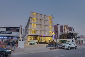 A multi-story hotel with a modern facade, a visible entrance, and a Coca-Cola sign.