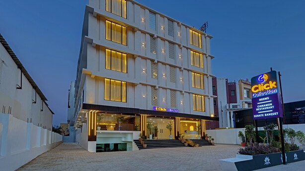 A multi-story hotel with a well-lit entrance and a signboard advertising amenities like rooms, a restaurant, and a banquet hall.