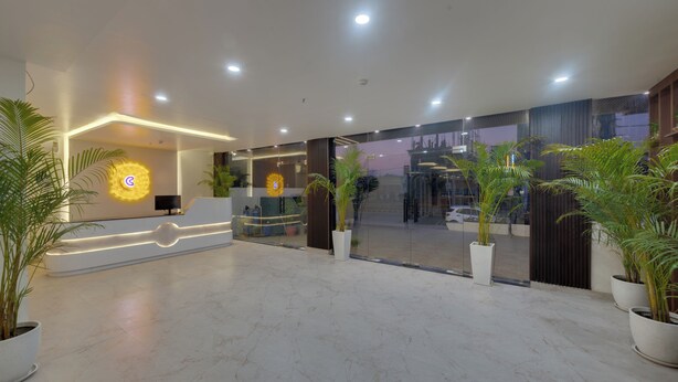 A modern hotel lobby with a reception desk, potted plants, and a glass partition. - Click Collection Ayodhya (Ayodhya)