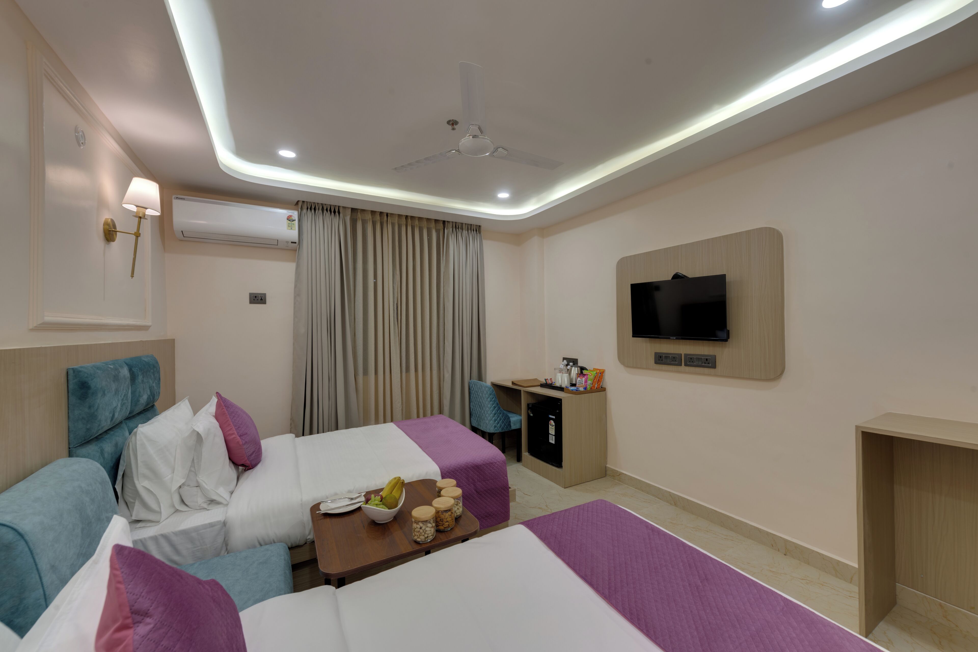 A hotel room with two beds, a desk, a chair, a TV, and a minibar.